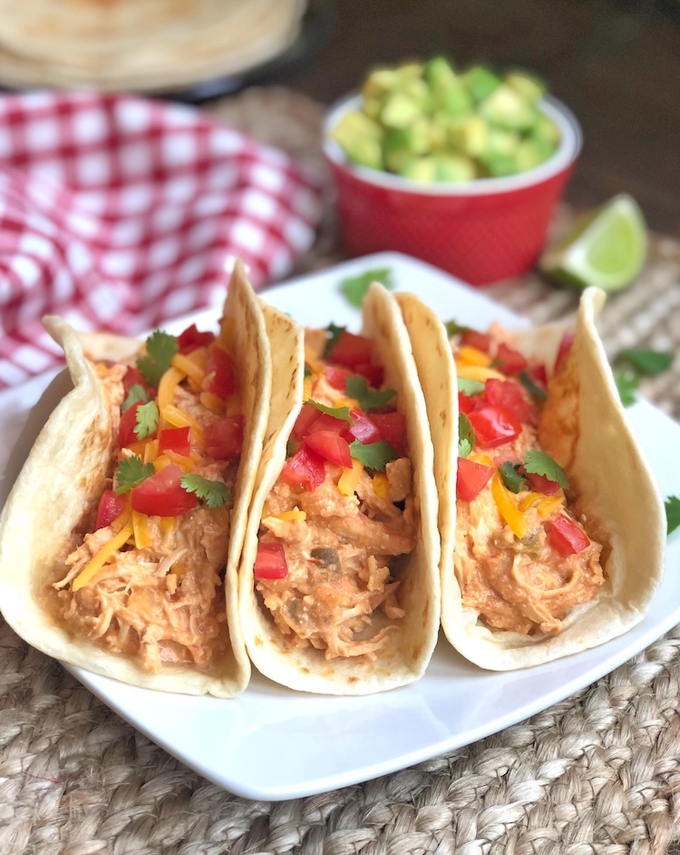 How to make creamy salsa shredded chicken tacos in your slow cooker! My family loves this easy weeknight dinner. Serve in warm flour tortillas to make the best homemade chicken tacos. Picky eater approved!